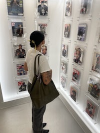 a woman looking at magazines on a wall